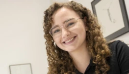Eine Frau mit Locken lächelt in die Kamera.