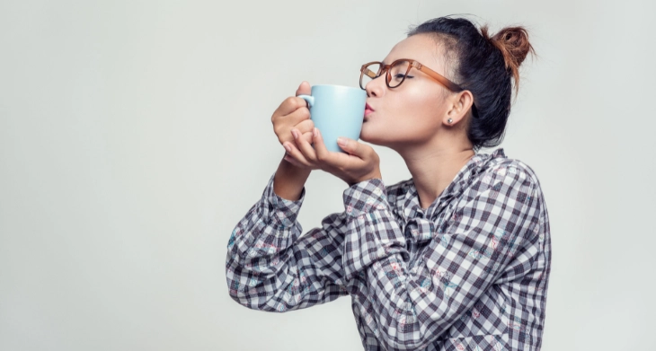 Frau küsst Kaffeetasse und genießt den Moment