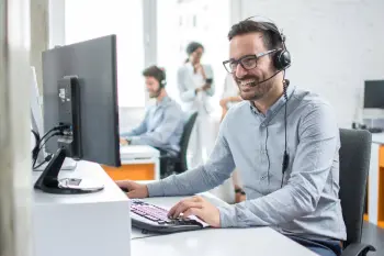 Ein Mann mit Headset sitzt vor einem PC und lacht.