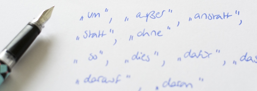 Wörter, vor denen Kommata stehen müssen, mit Füller auf ein Blatt geschrieben