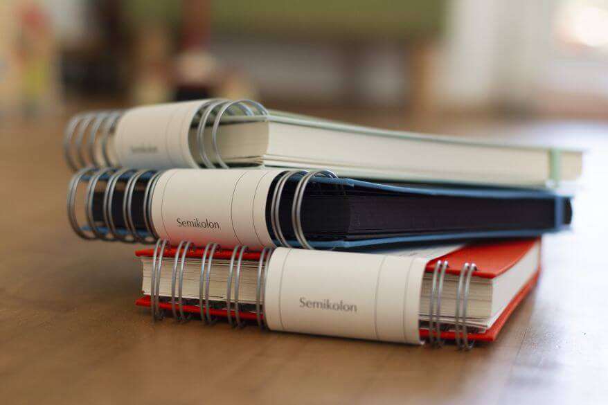 Drei Fotoalben Mini Mucho von Semikolon in verschiedenen Farben liegen gestapelt übereinander.