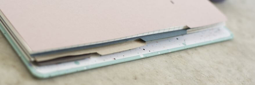 Nahaufnahme eines Notizbuchs von Filofax. Man blickt seitlich auf selbstgemachte Divider, die im Notizbuch eingeheftet sind.