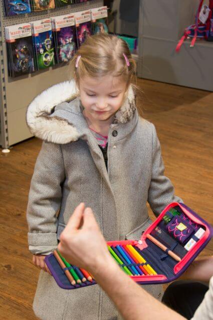 Ein Mitarbeiter erklärt einem Mädchen während einer Schulranzen Beratung, was alles in das Federmäppchen von ergobag gehört.