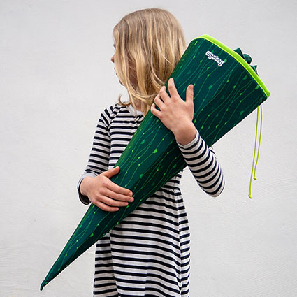 Ein Mädchen mit einer grünen Schultüte der Marke ergobag in der Hand guckt nach hinten.
