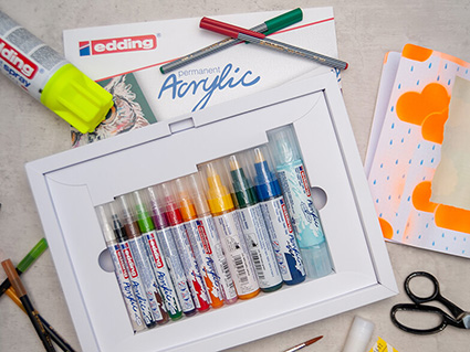 Auf einem hellen Untergrund liegen verschiedene Materialien und Stifte der Marke Edding, die zur Herstellung einer Seite in einem Art Journal im Mixed-Media-Stil verwendet wurden. Foto: Johanna Rundel