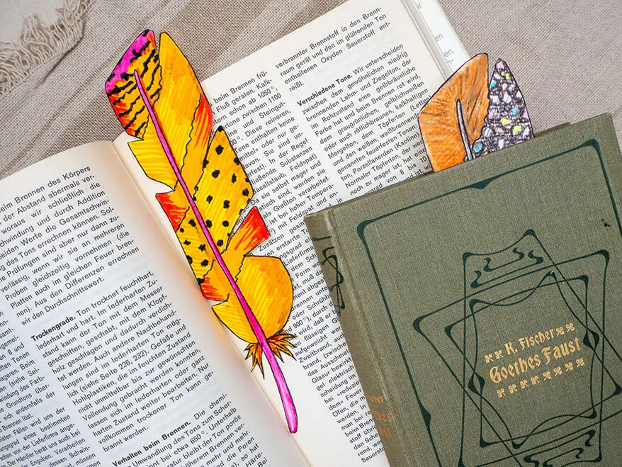 In zwei Büchern liegen selbstgemalte Lesezeichen in Form einer Vogelfeder. Sie wurden mit den Stiften von Faber-Castell gestaltet. Foto: Johanna Rundel