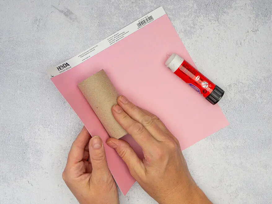 Jemand wickelt eine leere Klopapierrolle in ein Stück Rosa Karton von HEYDA ein. Foto: Johanna Rundel 