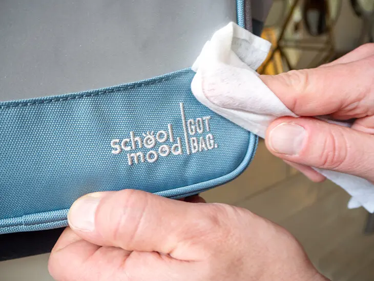 (Jemand wischt mit einem Feuchttuch die Außenseite eines blauen Schulranzens von School Mood ab. Foto: Johanna Rundel)