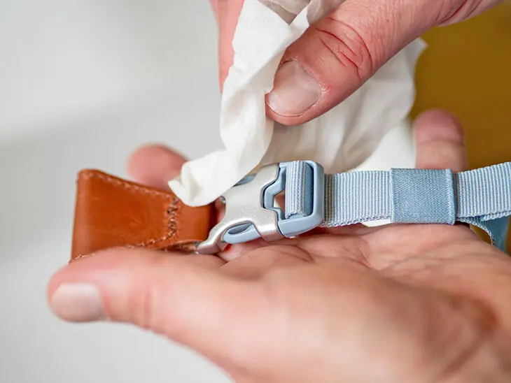 Jemand wischt eine silberne Steckschnalle eines hellblauen satch Schulrucksacks mit einem Feuchttuch sauber. Foto: Johanna Rundel