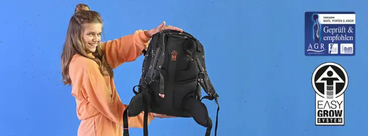 Ein Mädchen hält einen Schulrucksack von coocazoo hoch, daneben sind zwei Ergonomiesiegel eingebunden.