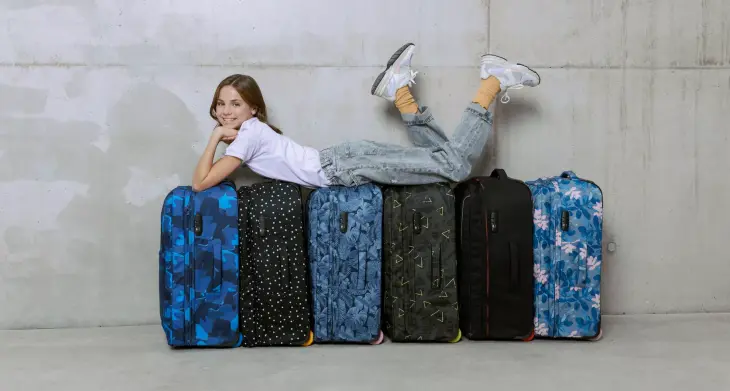 Ein Mädchen liegt auf mehreren aufgestellten Trolleys des satch flow und lacht in die Kamera.