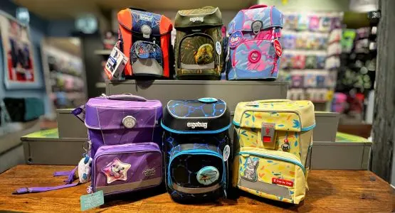 Viele bunte Schulranzen der Marken ergobag, Step by Step und Scout stehen im Regal und davor.