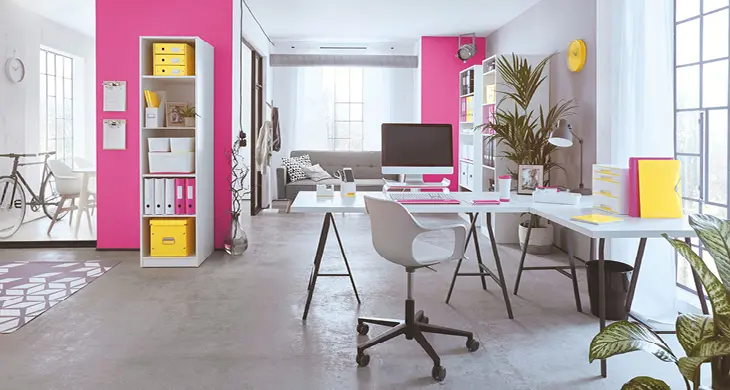 Loftartiges Wohnzimmer: weißer Schreibtisch mit weißem Drehstuhl und Büromaterial von Leitz, im Hintergrund Regale mit Ordnern und Boxen.