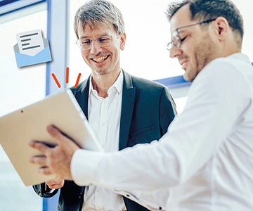 Zwei Männer schauen auf Tablet.