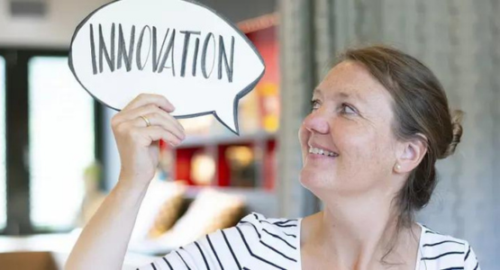 Eine Frau hält eine Sprechblase in die Luft, in der das Wort „Innovation“ steht.