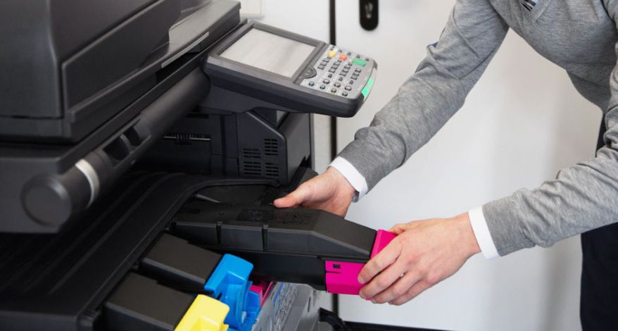 Jemand setzt eine Druckerpatrone in einen Multifunktionsdrucker ein. 