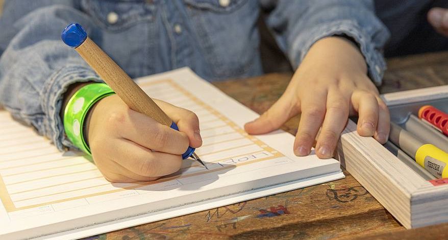 Detailfoto: Eine Kinderhand schreibt mit einem Schreiblernfüller von Lamy in ein Schreiblernheft.