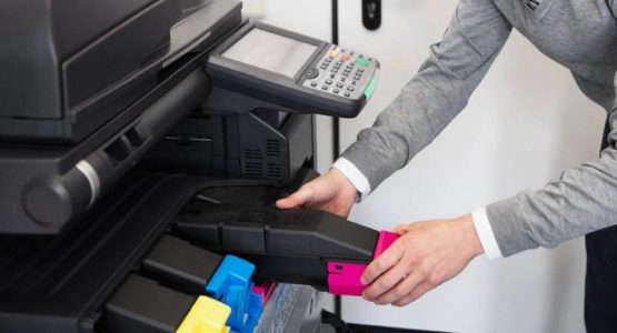 Jemand setzt eine Patronenkartusche in einen Drucker ein.