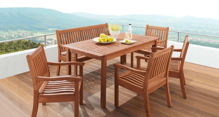 Holz-Gartenmöbel-Set mit Tisch, Stühlen und Bank auf einer Terrasse mit Panoramablick.