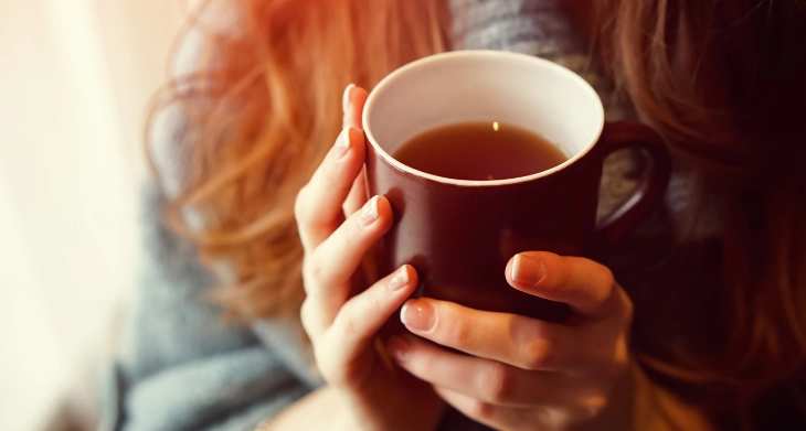 Frau hält Tasse mit Tee in den Händen