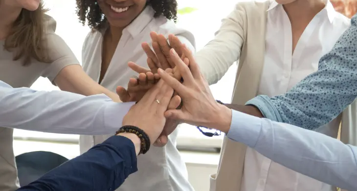 Mehrere Hände schlagen ein und geben sich ein High Five.