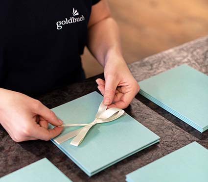 Jemand bindet eine Schleife um ein Fotoalbum der Marke Goldbuch.