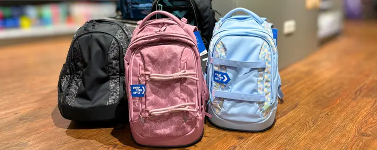 Verschiedene Schulrucksäcke von coocazoo und satch stehen auf mehrfarbigen Kacheln.