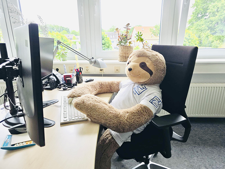 Ein Plüschbär sitzt vor einem Bildschirm und tippt auf der Tastatur.