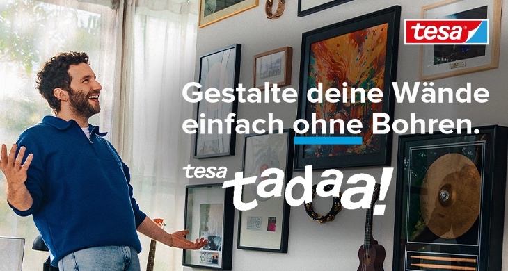Ein junger Mann mit blauem Sweatshirt steht in einem Raum mit vielen gerahmten Kunstwerken an der Wand. Der Text auf dem Bild lautet: "Gestalte deine Wände einfach ohne Bohren mithilfe von tesa Klebenagel. tesa tadaa!" In der rechten oberen Ecke befindet sich ein "tesa" Logo