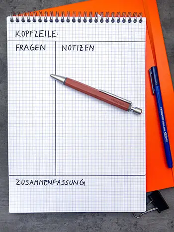 Auf einem Notizblock ist ein Blatt entsprechend der Cornell-Methode in Kopfzeile, Fragen, Notizen, Zusammenfassung eingeteilt.