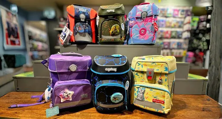 Viele bunte Schulranzen der Marken ergobag, Step by Step und Scout stehen im Regal und davor.