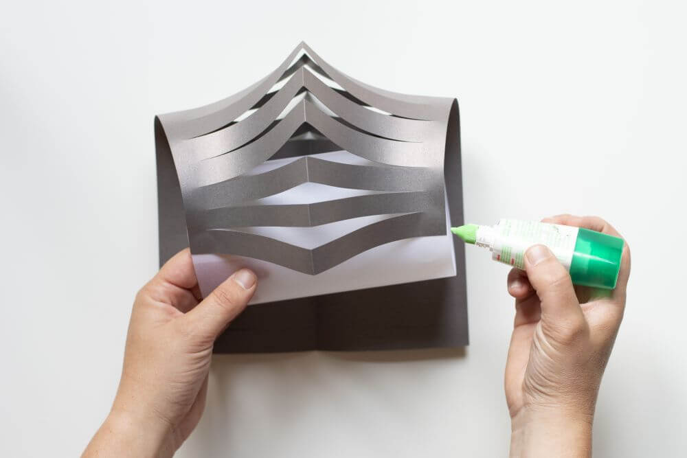 Laterne basteln aus Papier, Bastelanleitung Schritt 5: Geben Sie oben und unten einen Tropfen Flüssigkleber auf den Zylinder aus Pergamentpapier und befestigen Sie eine Seite des Tonpapiers am Zylinder.