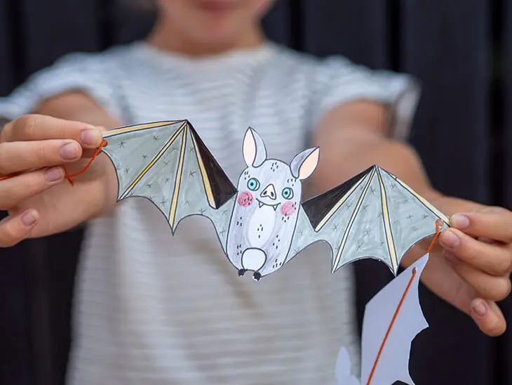Ein Kind hält eine gemalte Fledermaus aus Papier ins Bild. Foto: Johanna Rundel