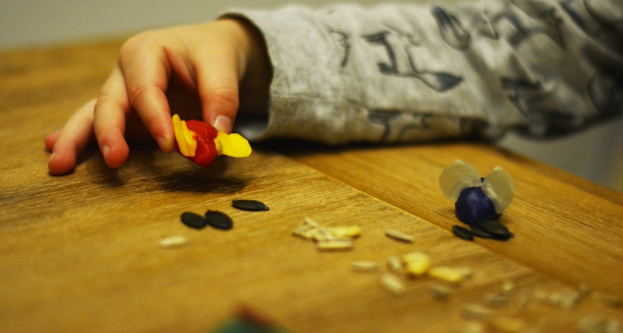 Eine Kinderhand hält eine aus Knetbienenwachs geformte Maus in der Hand. Auf dem Tisch vor ihm steht eine weitere Maus aus Knetbienenwachs.