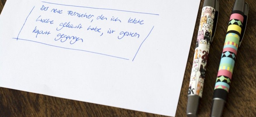 Auf einem Blatt ist ein Satz mit Füller geschrieben, daneben liegen 2 bunte Füller der Marke Online.