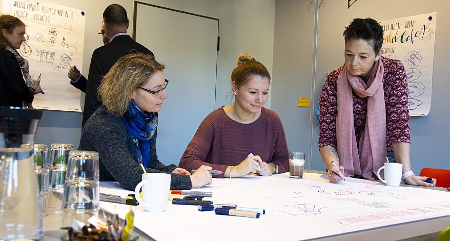 Mitarbeiter sitzen in einer Workshop-Situation an einem Tisch