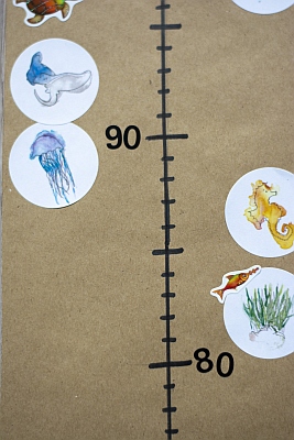 Nahaufnahme selbstgebastelter Messlatte mit bunten Aufklebern. 