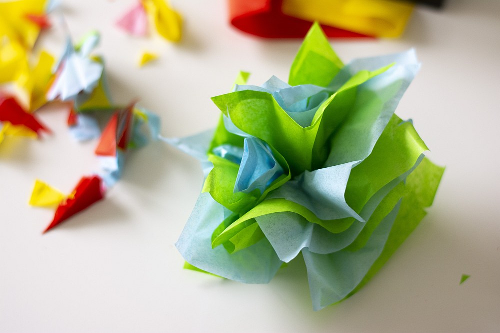 Bunte Papierblumen und Konfetti auf weißem Untergrund