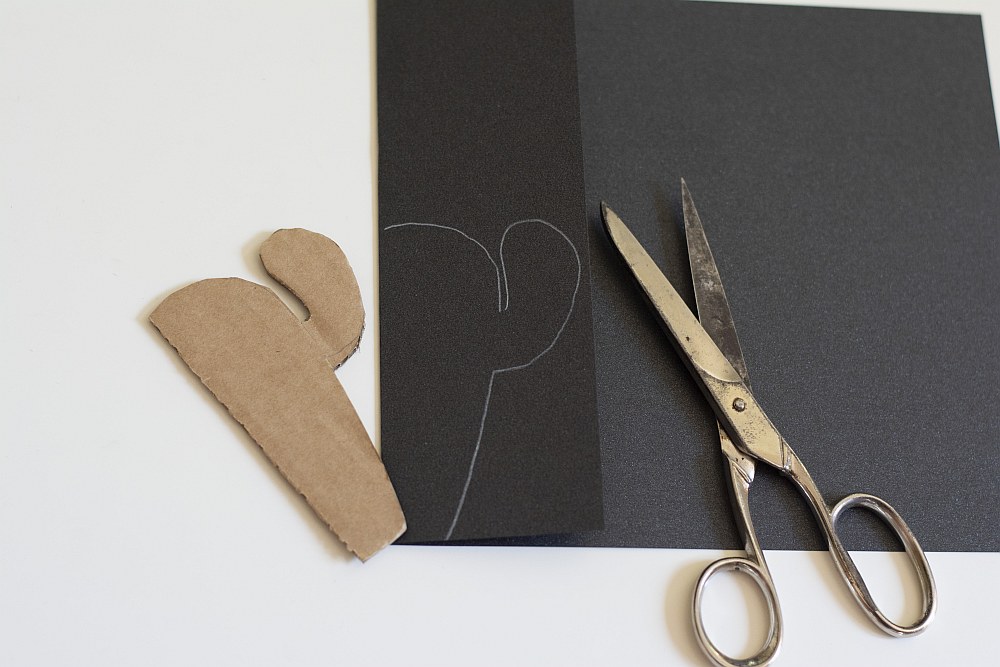 Kaktusschablone aus Pappe auf schwarzem Papier mit Schere