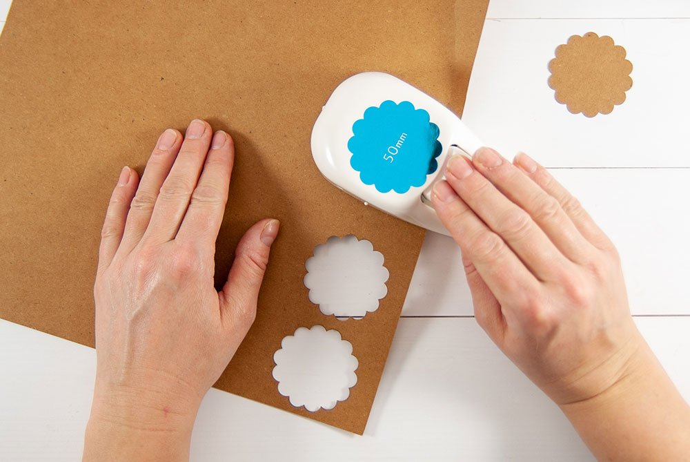 Mit Hilfe eines Motivstanzers der Marke Artoz werden Wellenkreise aus einem braunen Karton ausgestochen. Der Untergrund ist weiß