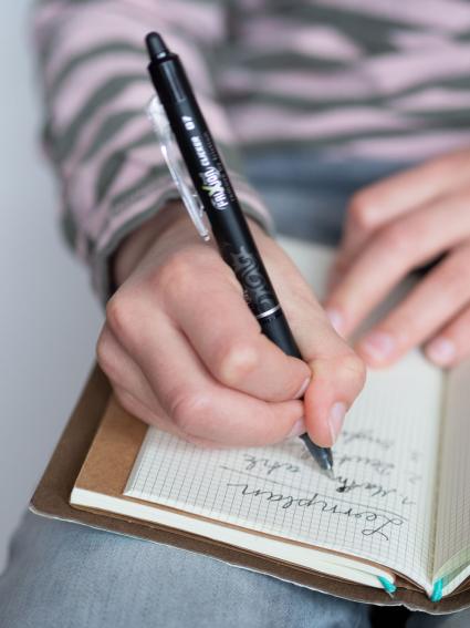Eine Hand screibt mit einem Frixion Pen von Pilot einen Lernplan in ein Heft. 