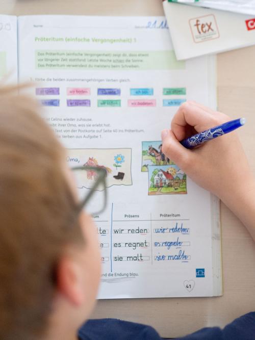 Ein Kind löst Aufgaben in einem Schulbuch mit Hilfe eines Frixion Pens von Pilot. 