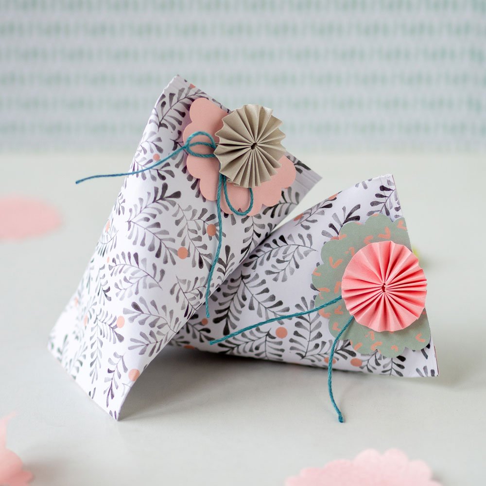 Zwei schön gefaltete und dekorierte kleine Geschenkschachteln lehnen aneinander.