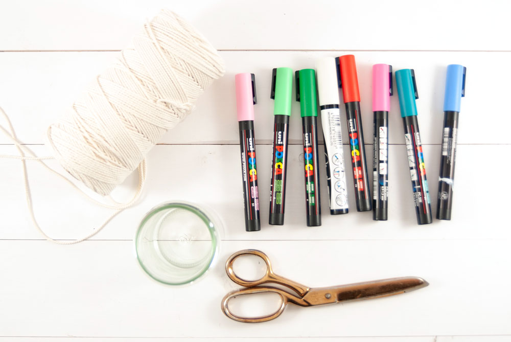 Bunte Stifte, Kordel, Glas und Schere auf einem Tisch