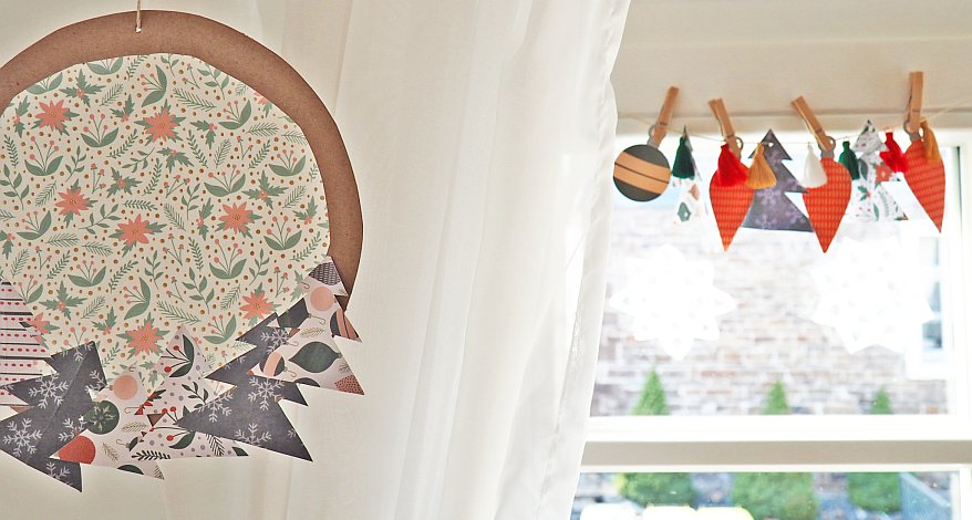 Weihnachtliche Papierdekoration hängt vor einem Fenster.