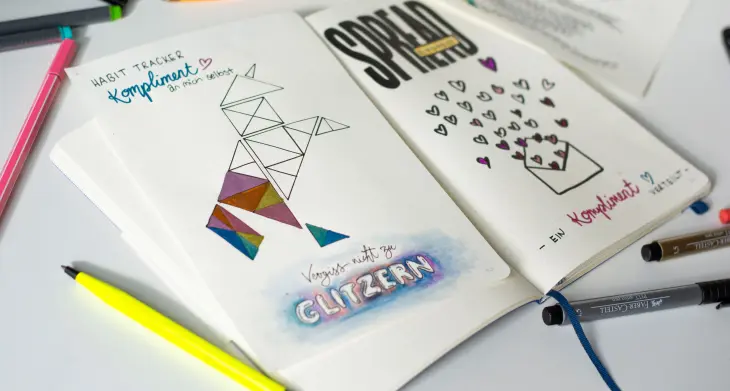 3 verschiedene Habit Tracker in einem Bullet Journal liegen aufgeklappt auf einem Schreibtisch.