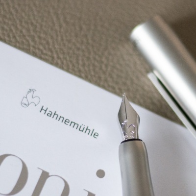 Nahaufnahme von Füllhalter, Notizbuch und Logo von Hahnemühle