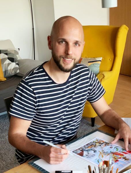 Illustrator Max Tiedtke sitzt am Schreibtisch und koloriert einen Comic.