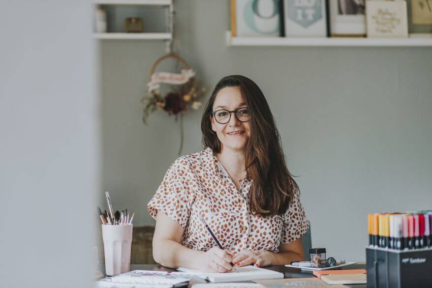 Portrait der Grafikdesignerin und Handlettering-Artist Kathrin-Nina Vinko an ihrem Schreibtisch.