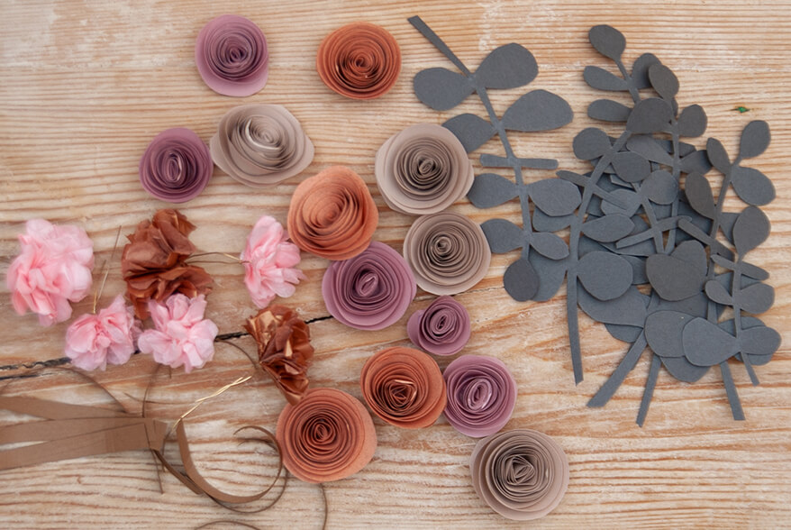 Auf einer hellen Holzoberfläche liegen verschiedene Papierblumen und -blätter, die aus den Papieren von Artoz gefertigt wurden. Foto: Johanna Rundel
